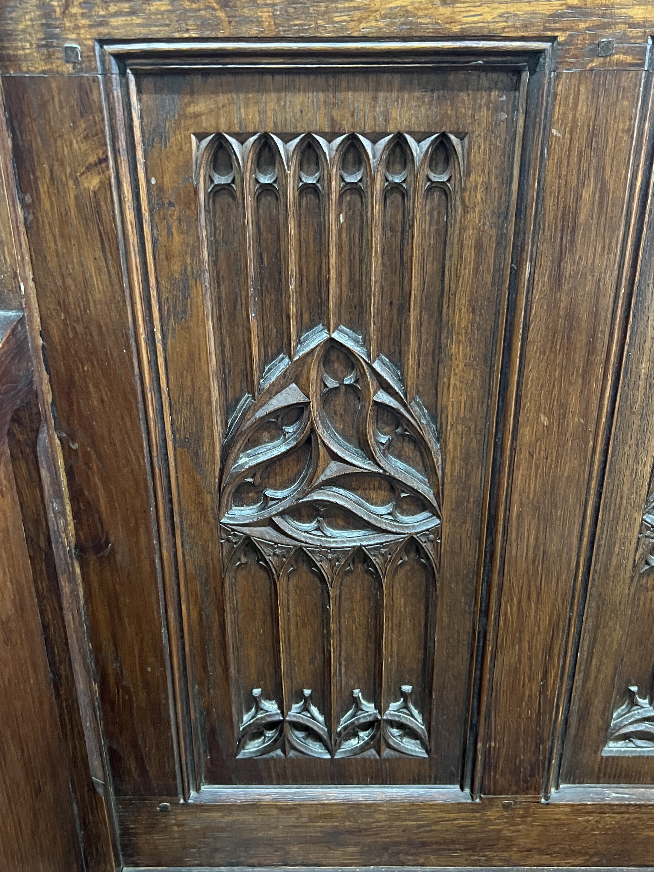 An early 20th century carved oak Gothic Revival settle with hinged box seat, width 137cm, depth 49cm, height 160cm